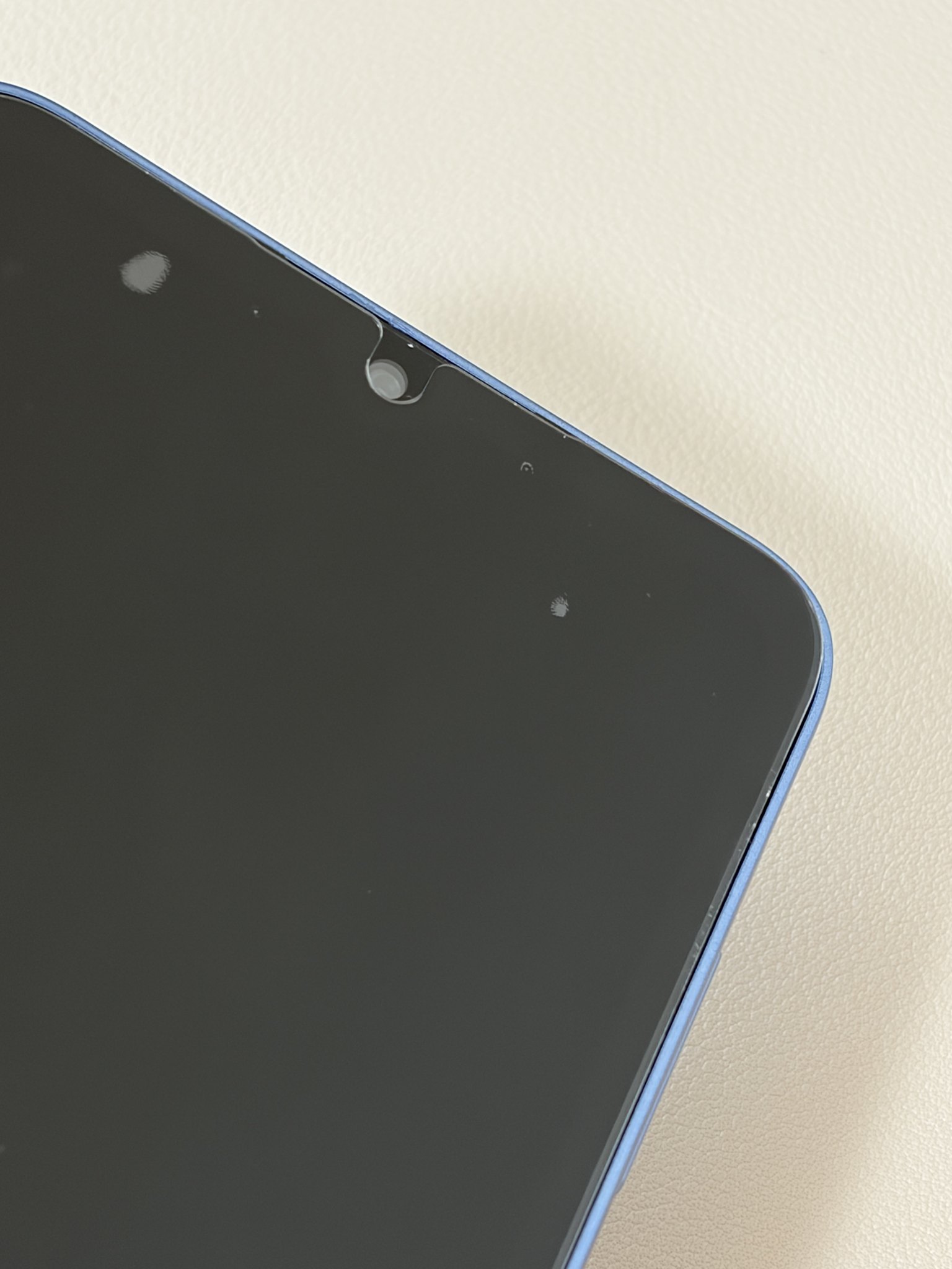 机に置いたGalaxy A25モックの上部。フロントカメラ穴とフィルムの位置