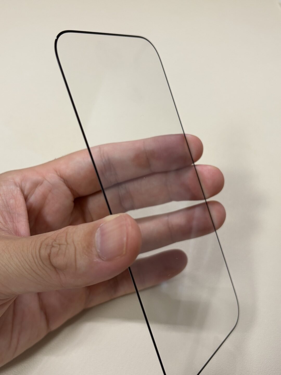ESR Armorite ガラスフィルム（iPhone 18 Pro用）を手に持った状態。黒い縁のフルカバータイプ